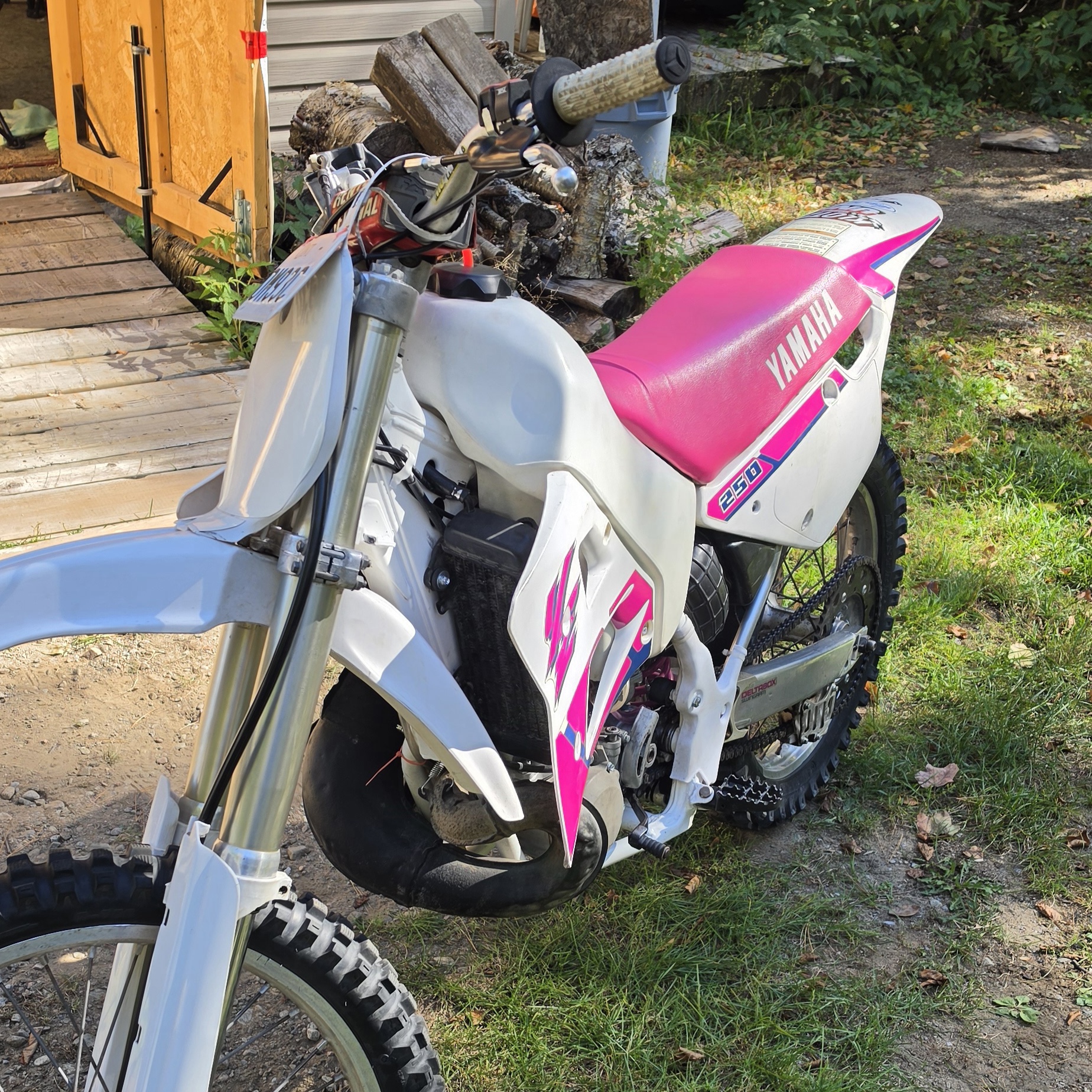 White Yamaha dirt bike with a pink seat outdoors